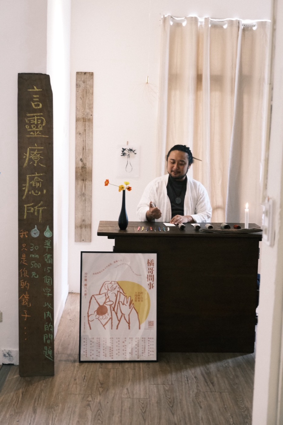 言靈療癒所的問事攤現場：木牌寫著準備15個字以內的問題，橘哥坐在木桌後